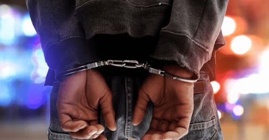 handcuffed in front of police car